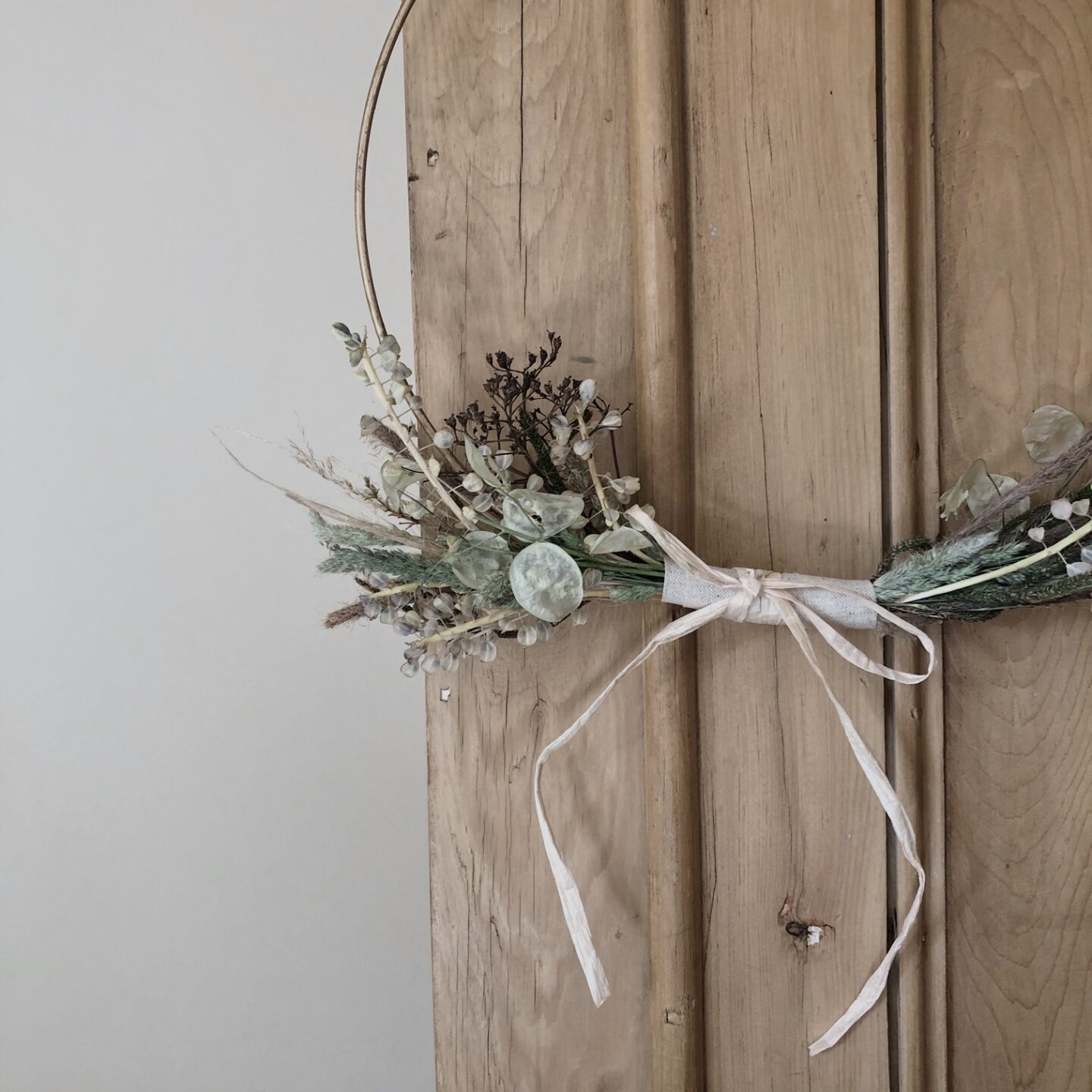 Dried flower wreath hanging against cupboard
