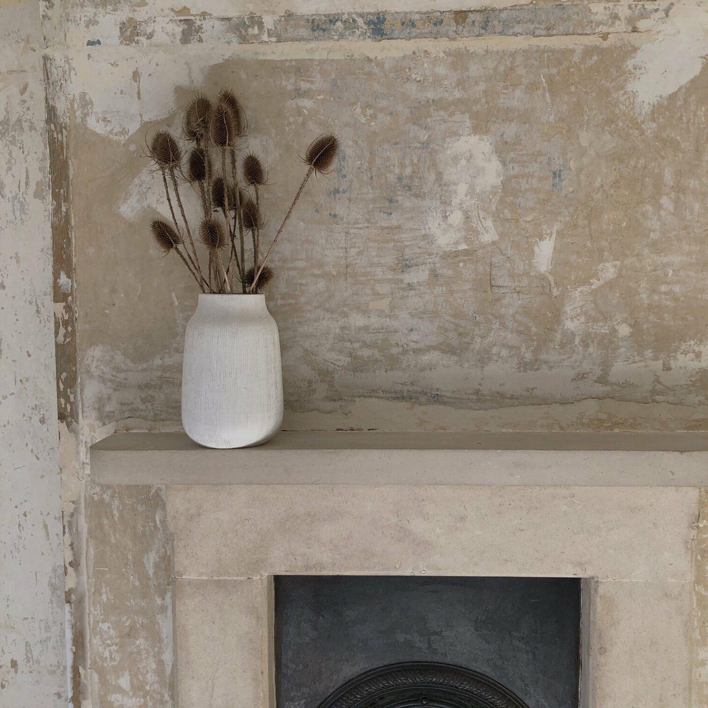 Rustic wallpaper-stripped walls and a vase of teasels 