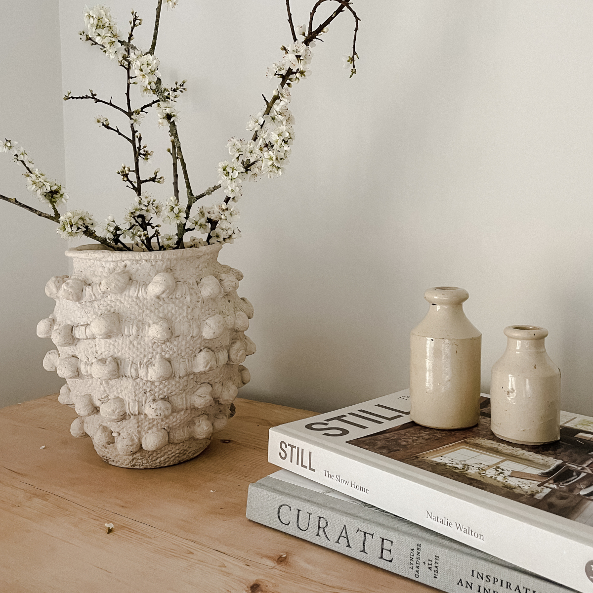 Vase of blossom and slow interiors books in a stack